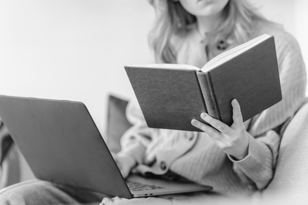 Woman reading a book with computer